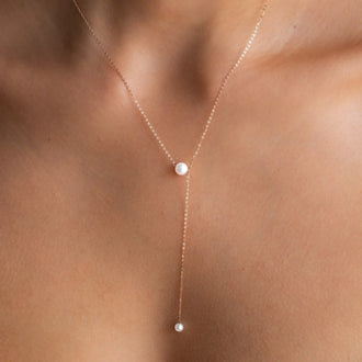close up of long necklace sadie in y-form with two 6mm akoya pearls in 18 kt rose gold worn on around womans neck