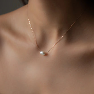 cleavage of woman wearing necklace hana with rose gold chain and big oval pearl pendant