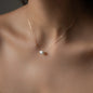 cleavage of woman wearing necklace hana with rose gold chain and big oval pearl pendant