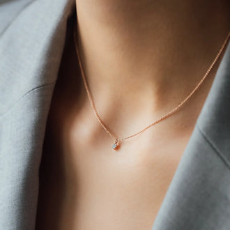 close up of woman’s cleavage wearing a grey blazer with necklace SOUL with a white diamond in rose gold