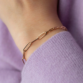 closeup of Bracelet Jackson with chain links in 18 KT rose gold worn on wrist of person in lilac sweater