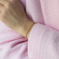 Bracelet LANA in yellow gold worn on womans wrist with pink jacket