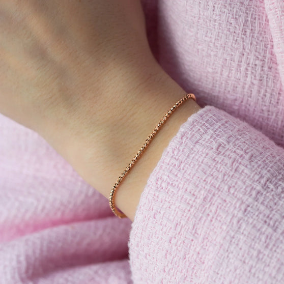 close up of Bracelet LANA in yellow gold worn on womans wrist with pink jacket