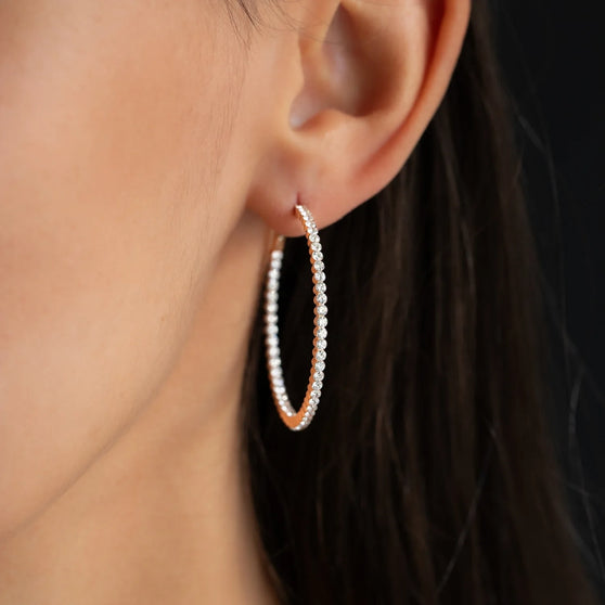 close up of hoop earring CHLOE 40mm with white diamonds in 18 kt rose gold worn on womans ear