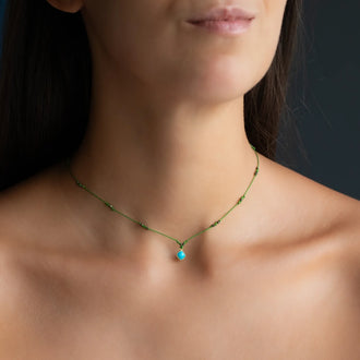 neck of woman wearing Chocker with green ribbon and 18 KT yellow gold pendant with gemstone turquoise 