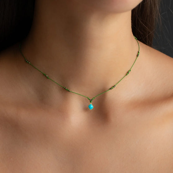 necklace BAY with green thread and turquoise pendant with yellow gold details worn around neck of woman