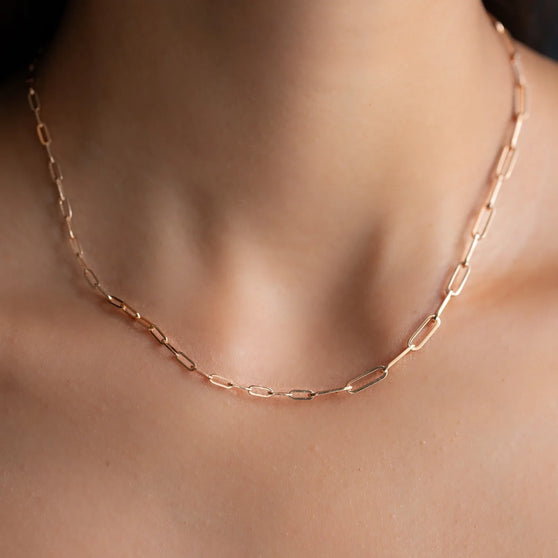 Close up of 18 KT rose gold chain link necklace with different sized chain links worn on woman