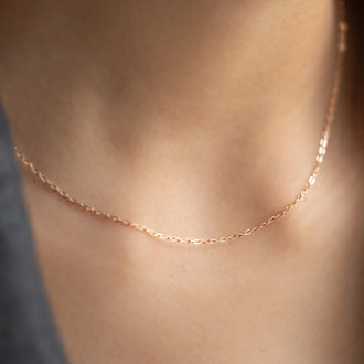 shiny gold necklace without pendant worn around neck