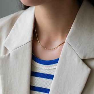 necklace lana in yellow gold worn on woman in striped shirt and blazer