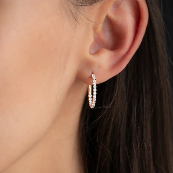 close up of hoop earring CHLOE 20mm with white diamonds in 18 kt rose gold worn on womans ear