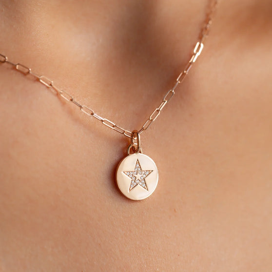 close up of cleavage with fine jewelry necklace in 18 kt rose gold with round coin pendant with star symbol  and white diamonds
