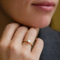 Close up of engagement ring FOREVER in yellow gold with many little diamonds on ring band and one big white diamond in heart shape worn on womans finger