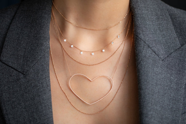 necklace layering in 18 KT Roségold with white diamonds and heart pendant worn on woman