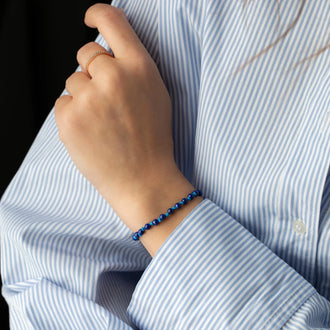 wristband Elliot with lapis lazuli pearls and 18 KT rose gold closure worn on woman in blue white shirt