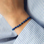 close up of wristband Elliot with lapis lazuli pearls and 18 KT rose gold closure worn on woman in blue white shirt