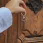 hand playing with eye shaped keychain in front of brown wood door