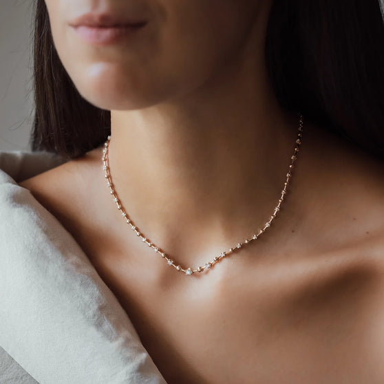 woman with dark hair wearing rosegold necklace with diamonds
