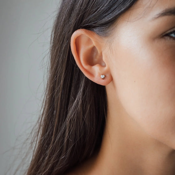 Woman wearing rose gold diamond ear stud in heart shape