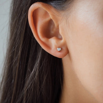 Woman wearing rose gold diamond ear stud in heart shape, detail