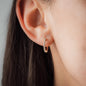 close up woman wearing white diamond creole earring CLAIRE 20mm in yellow gold