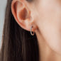 close up of woman wearing white diamond creole earring CLAIRE 20mm in white gold