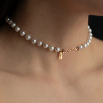 Close up of Necklace LAURY in grey and rose gold with pearls all around worn from woman