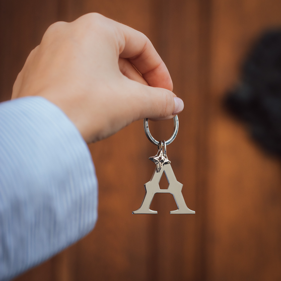 closeup of womans hand with steel keychain with letter a 