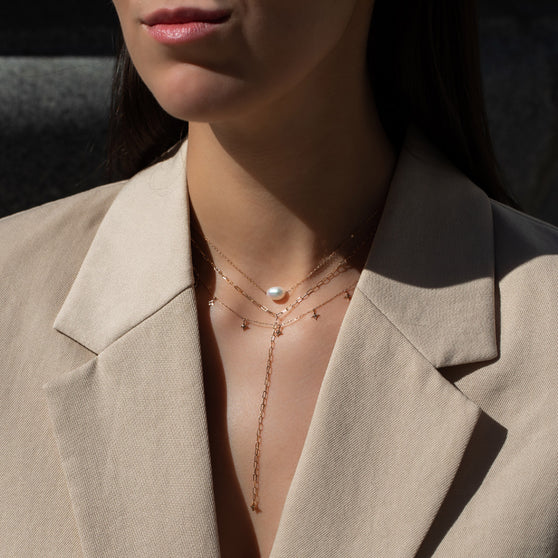 woman in beige blazer wearing necklaces in layering with necklace Hana with white pearl, necklace ANNA Signature Star 7 and necklace Lenox Eve in Roségold