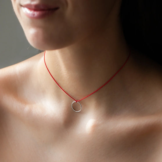 necklace LEXI with round pendant in sterling silver and red thread worn on womans neck