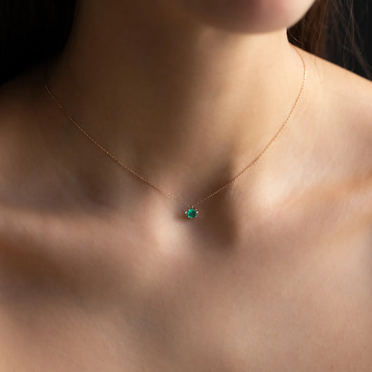 cleavage of woman with rose gold necklace mavis with green gemstone and white diamonds