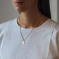 Necklace Nala in rose gold with green details worn from woman with white shirt
