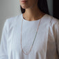 Necklace Nala in rose gold with green details worn from woman in white shirt