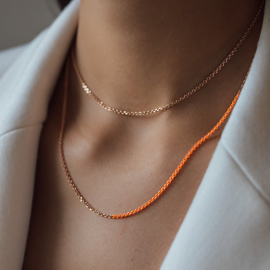 Necklace Nala in rose gold with orange details worn from woman in white blazer