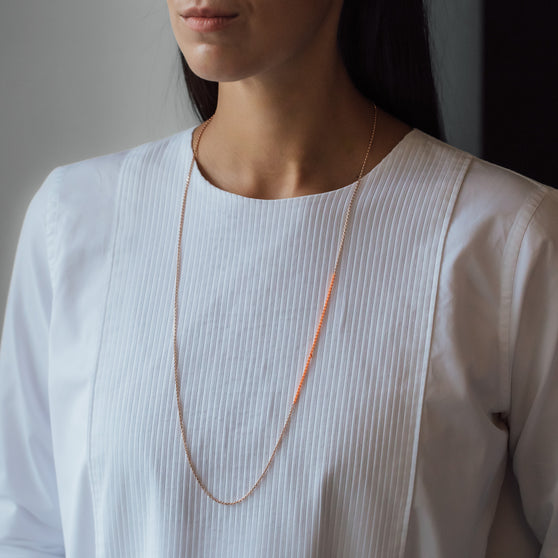 Necklace Nala in orange gold with pink details worn from woman in white shirt