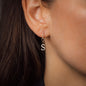 detail of diamond earring with letter S on woman with dark hair