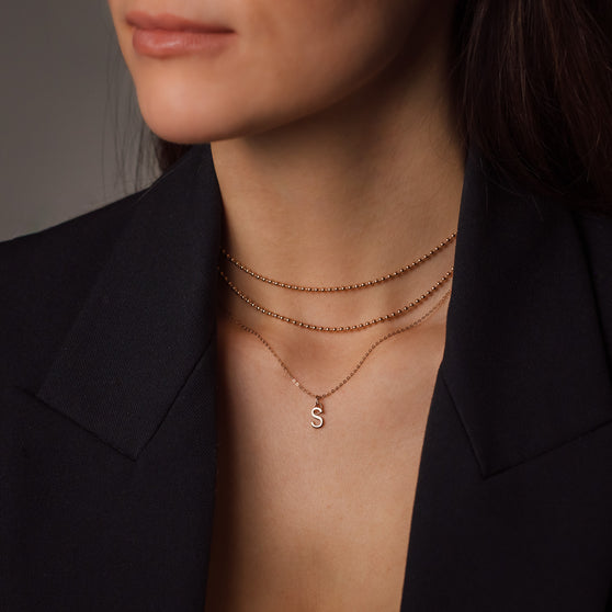 woman wearing black blazer and rosegold necklaces