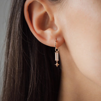 Detail of woman ear with earring in rose gold an morganite pendant