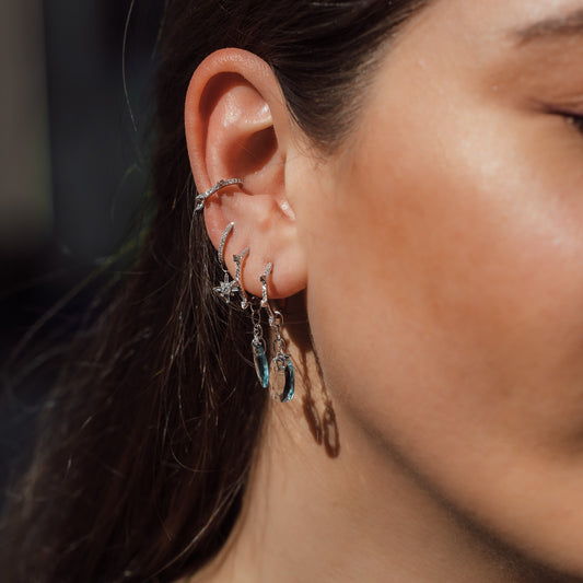 womans ear with diamond earrings and blue stone details