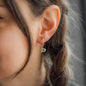 woman with braids wearing diamond earring with green stone pendant and rosegold star pendant
