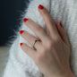 hand of woman with yellow gold wedding ring and red nail polish on white background