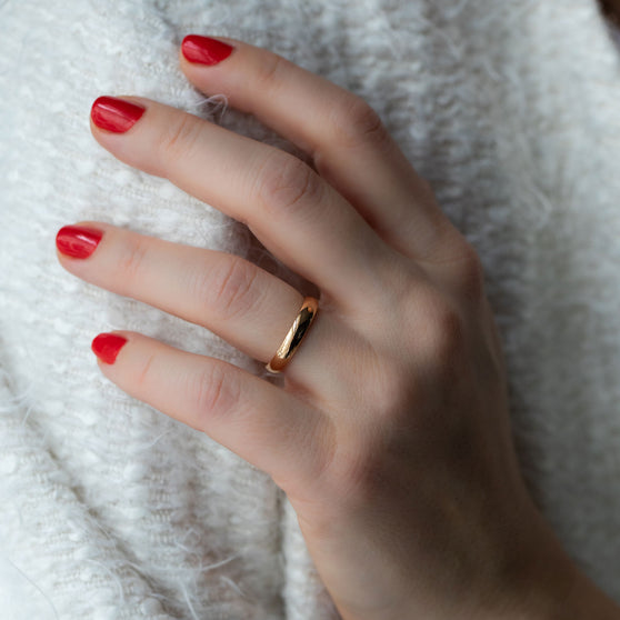 Wedding ring BELOVED in rose gold worn on womans hand with red nail polish