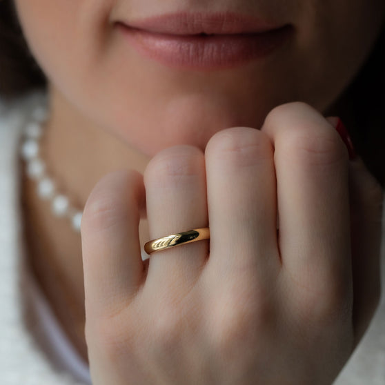 woman with chin on hand wearing yellow gold wedding ring 