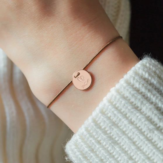 wrist with brown wristband with engraved pendant with rabbit symbol