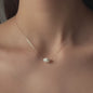 cleavage of woman wearing necklace hani with rose gold chain and big oval pearl pendant