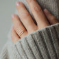 womans hand with rosegold ring and knit sleeve